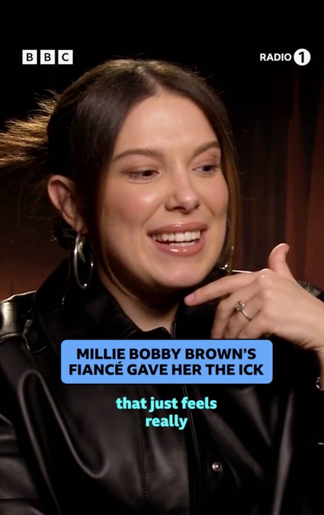 Millie Bobby Brown in a black jacket smiling during an interview, with a caption about her fiancé&#x27;s fragrance