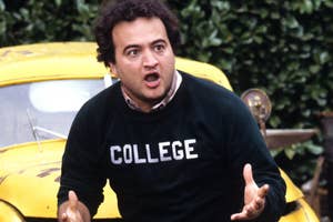 John Belushi in 'COLLEGE' sweater, expressive, standing by yellow car