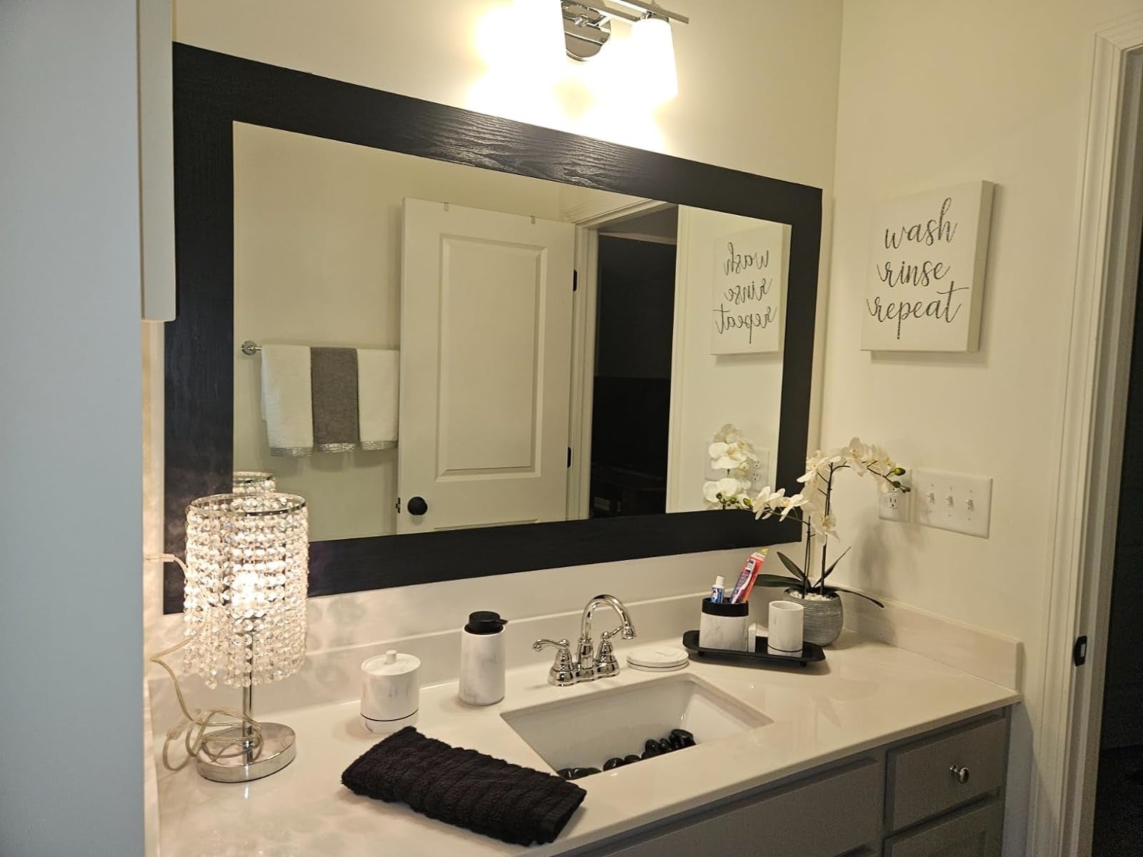 A well-lit bath  vanity with mirror, decorative lamp, and substance   partition  creation  saying 
