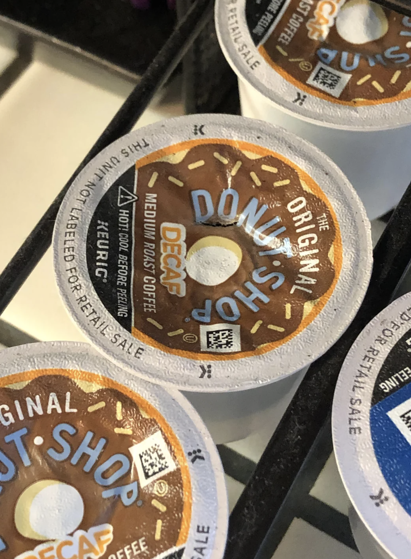Three stacked coffee pods with a donut shop design, labeled as medium roast decaf. A QR code is visible