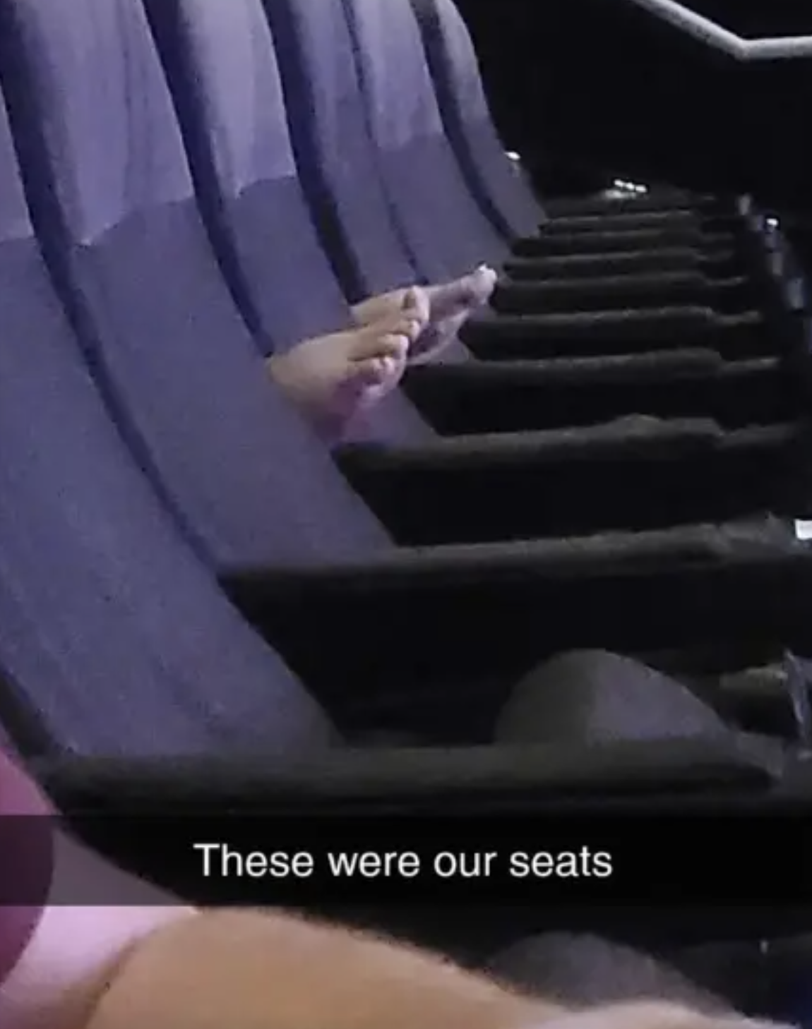 Photo of several empty theater seats with a person&#x27;s hand indicating their assigned seating area; text overlay &quot;These were our seats&quot;