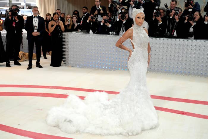 Kim Kardashian en un evento de gala, lleva un vestido ajustado con cola y posa para fotógrafos