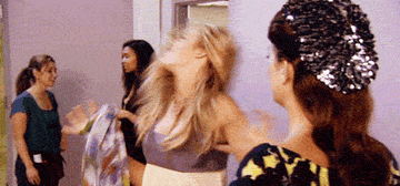 Animated gif of a reality TV show scene with four women, one tossing her hair back