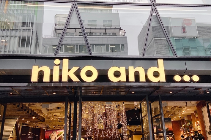 Storefront of "niko and..." with clothing and items visible through glass façade
