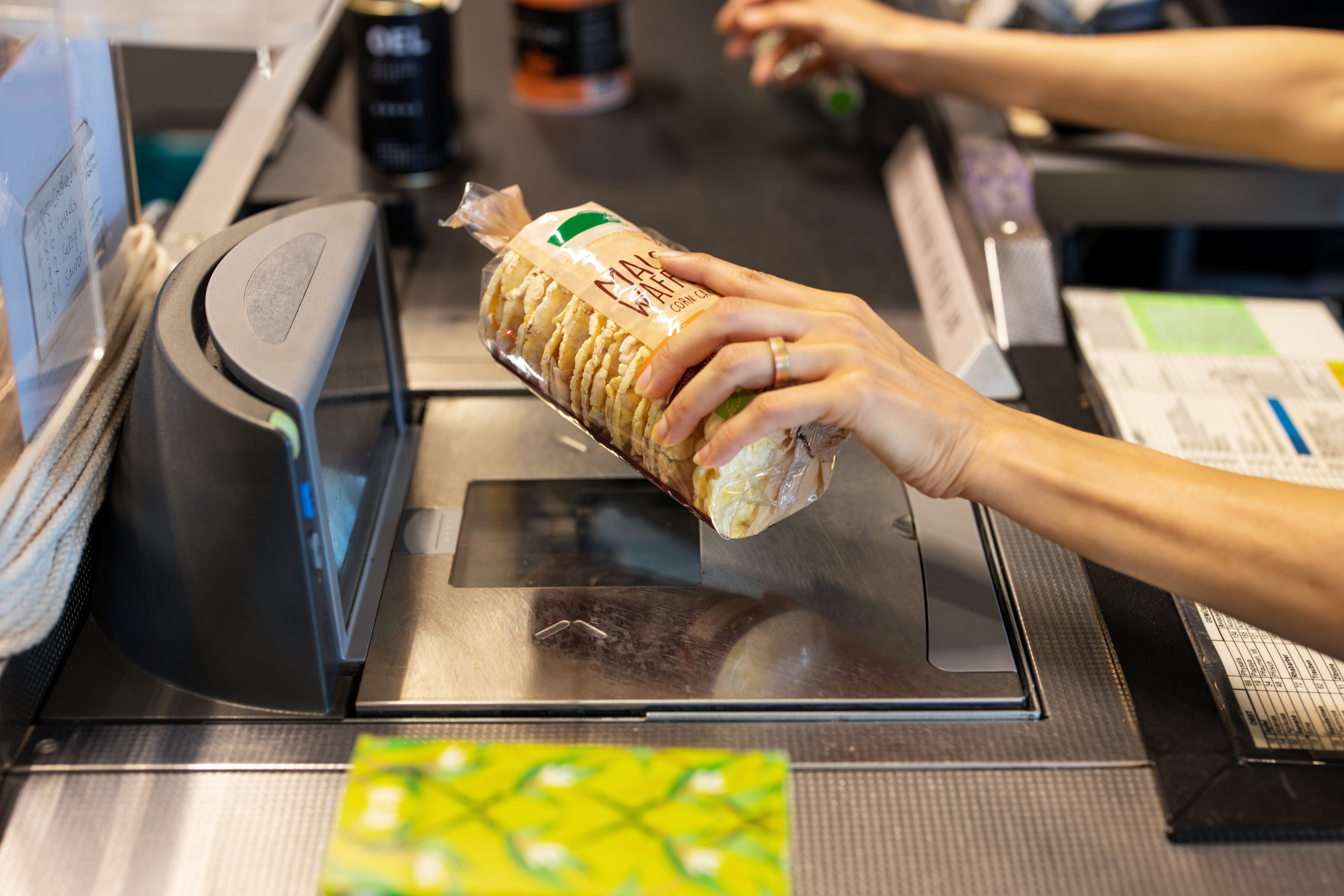 Hand scanning grocery item over a checkout counter