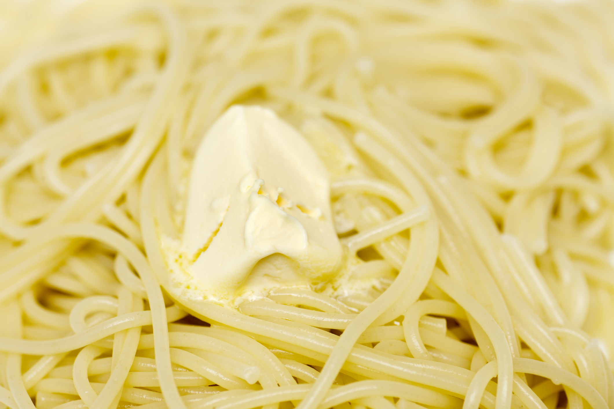 Cooked spaghetti noodles with a dollop of butter melting on top