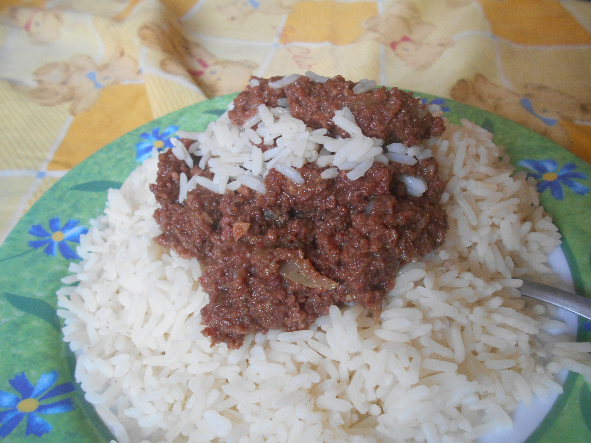 A plate of white rice topped with a spoonful of minced meat sauce