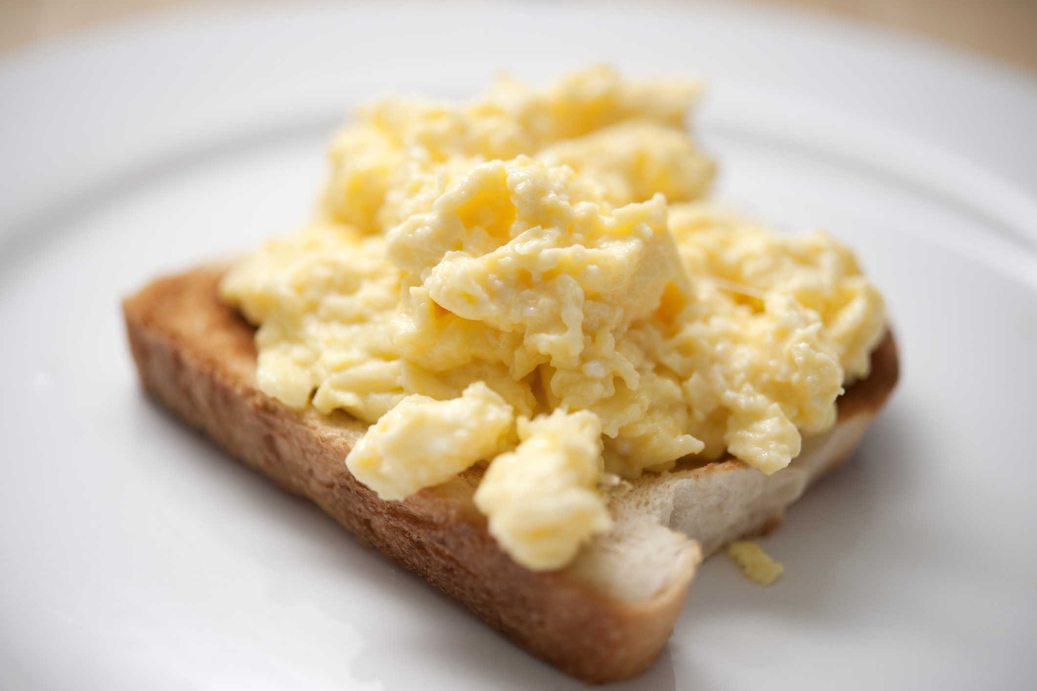 Scrambled eggs on toast served on a white plate
