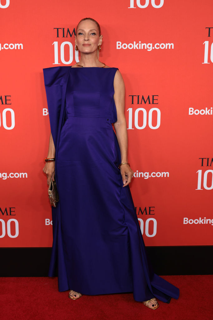 Uma Thurman at an event, wearing an elegant sleeveless blue gown with ruffle detail, posing on the red carpet