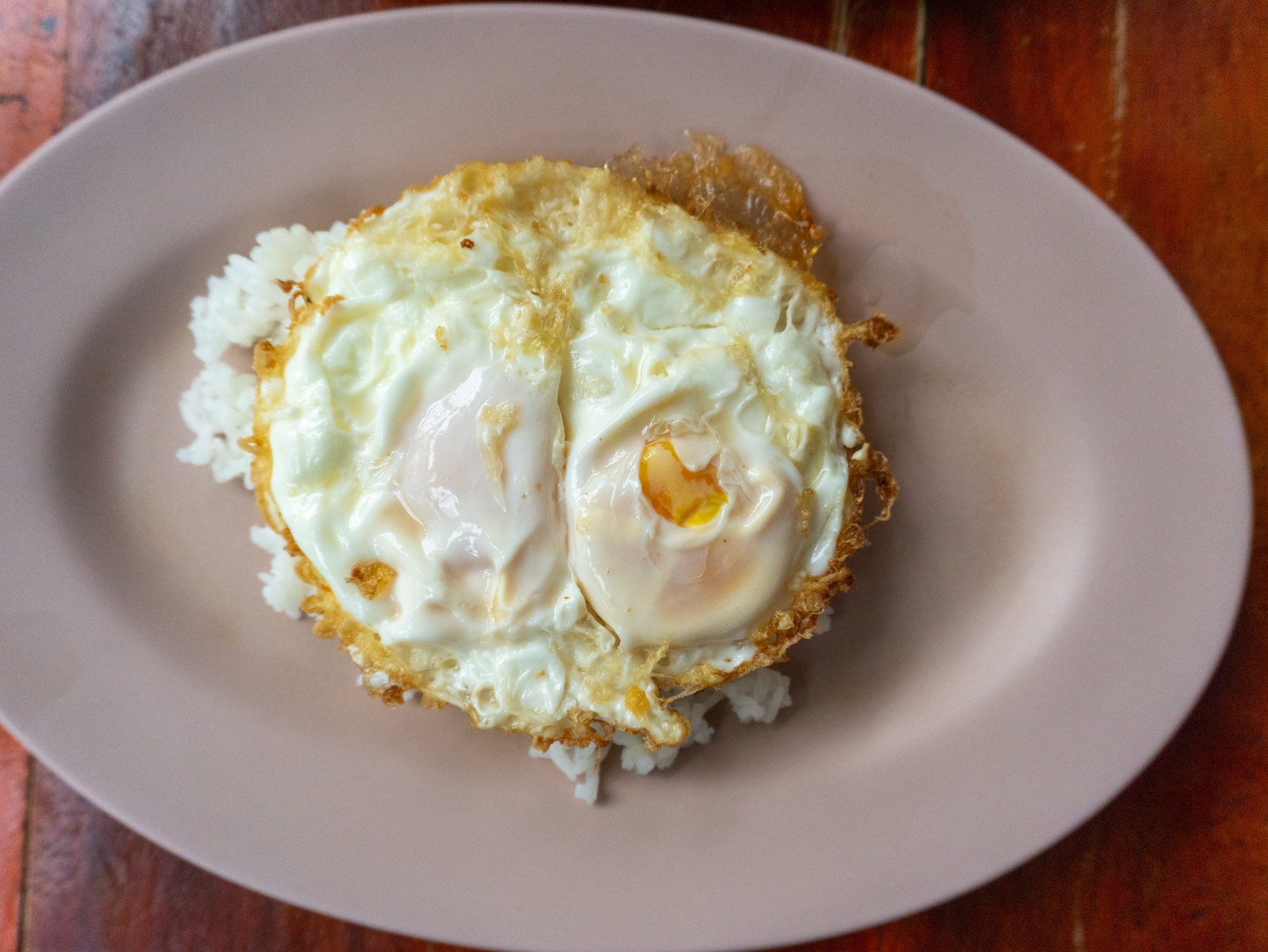 Plate with rice topped with a fried egg on a wooden table