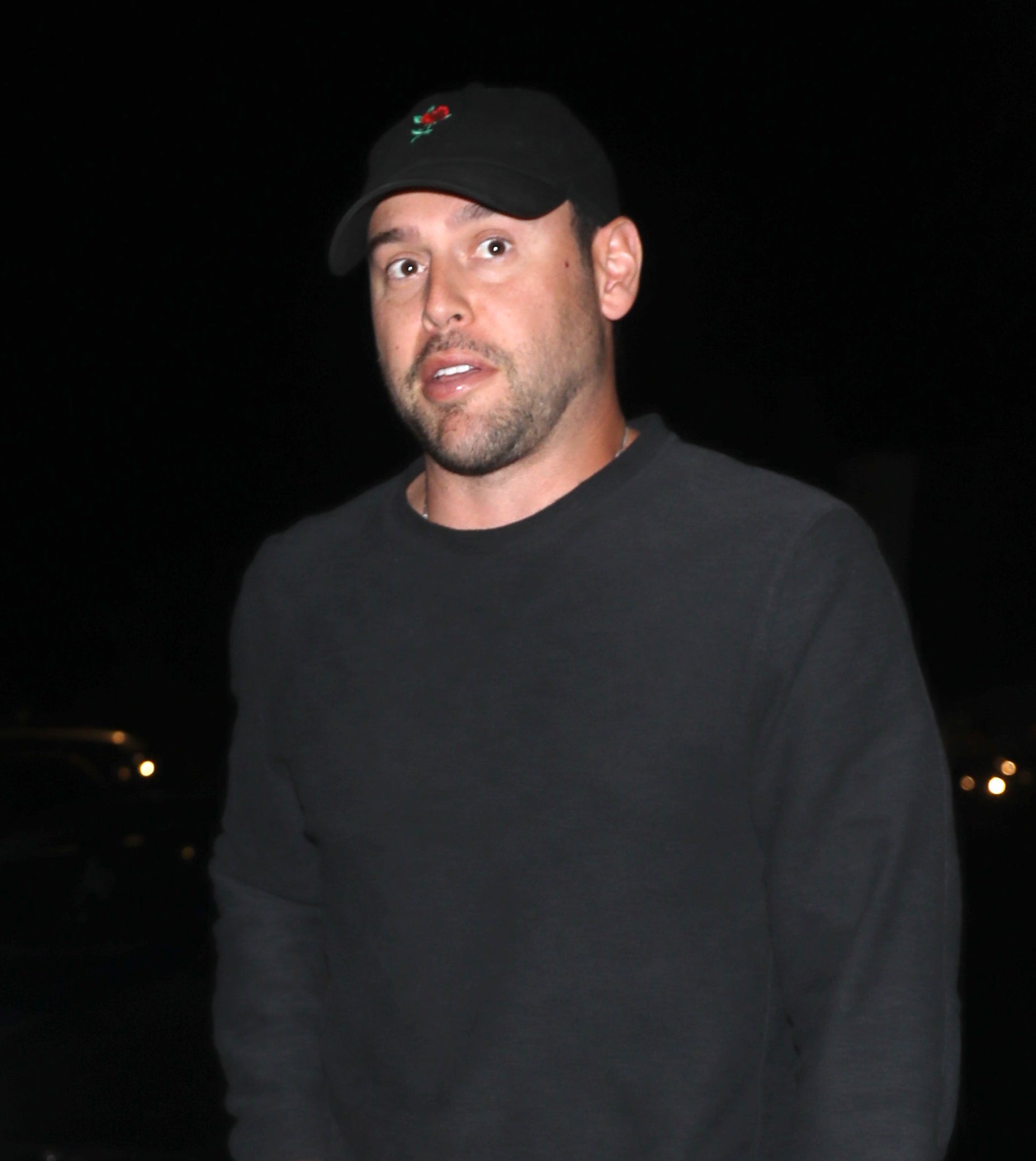 Scooter Braun in a casual sweater and pants walking on a city street at night
