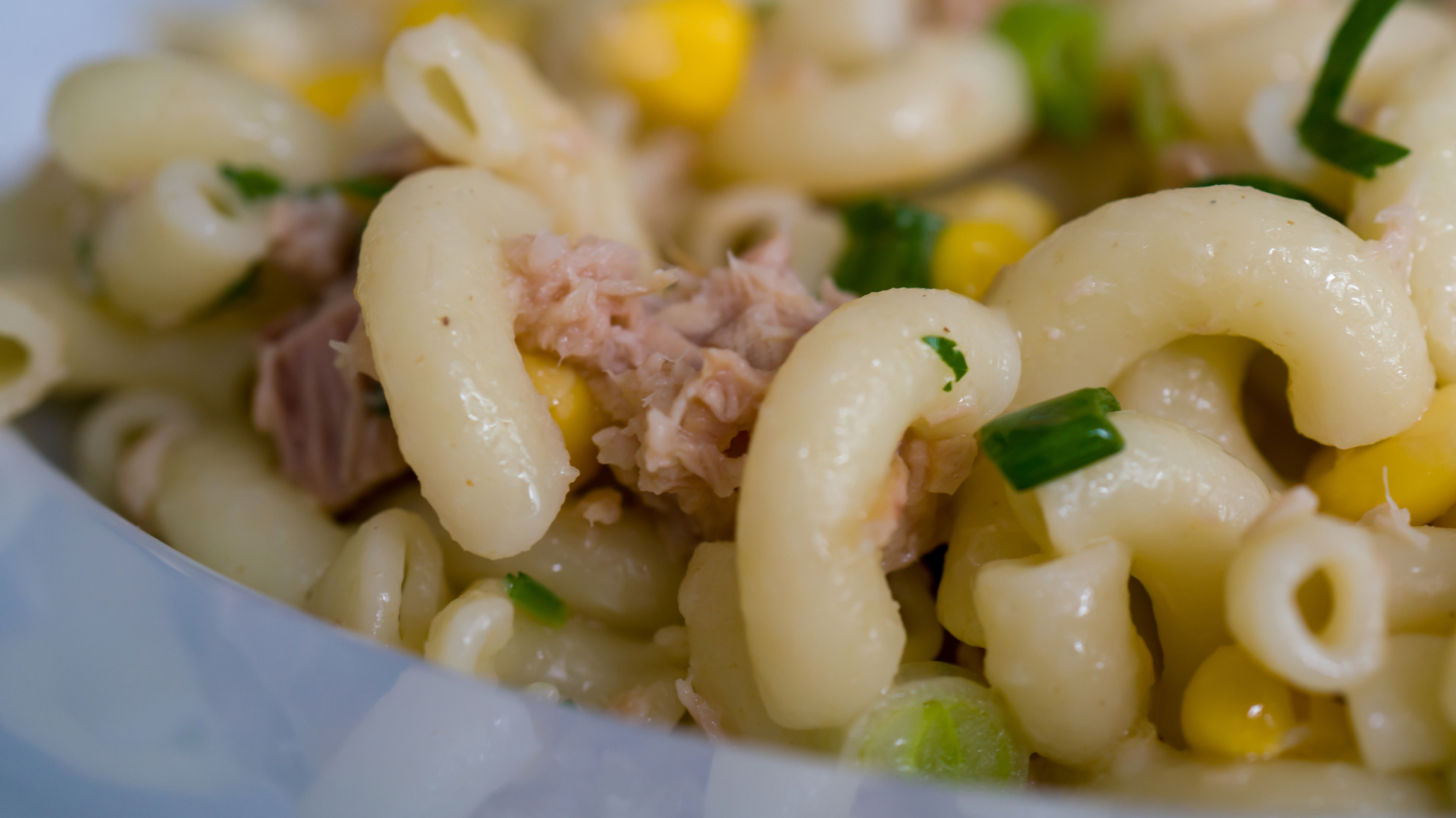 A close-up of a tuna macaroni salad with corn and diced green onions