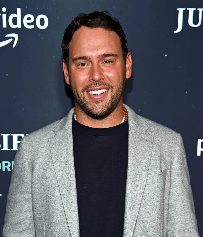 Scooter Braun in a grey blazer over a black shirt posing at an event