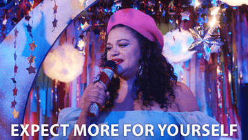 Gif of someone in a beret performing onstage with a microphone, backdrop with stars and tinsels, captioned &quot;EXPECT MORE FOR YOURSELF&quot;