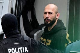 Man in hoodie escorted by police, looking at the camera