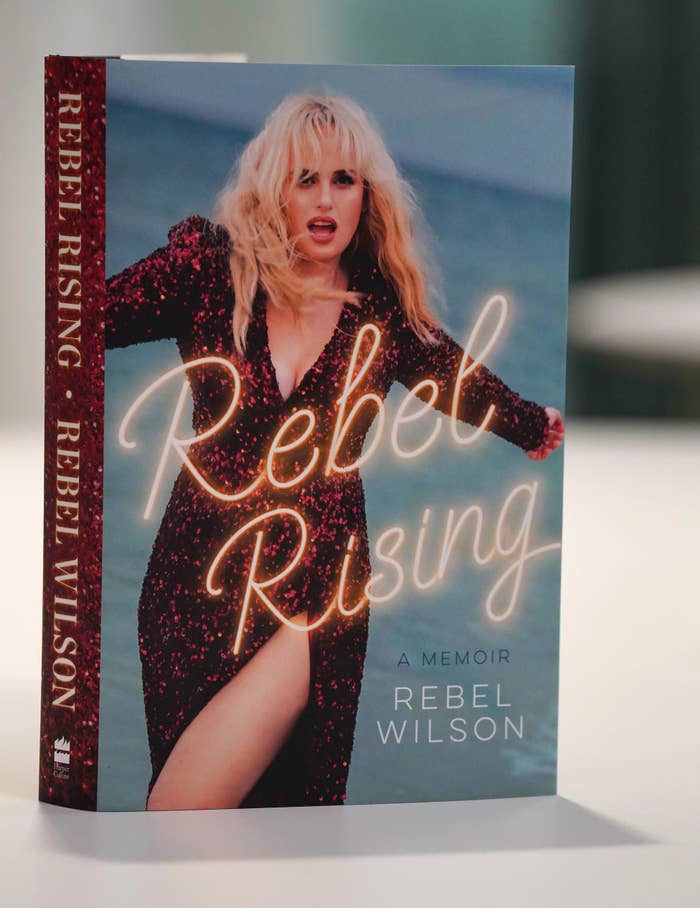 Book cover featuring Rebel Wilson for her memoir &quot;Rebel Rising.&quot; She poses confidently in a glittery outfit