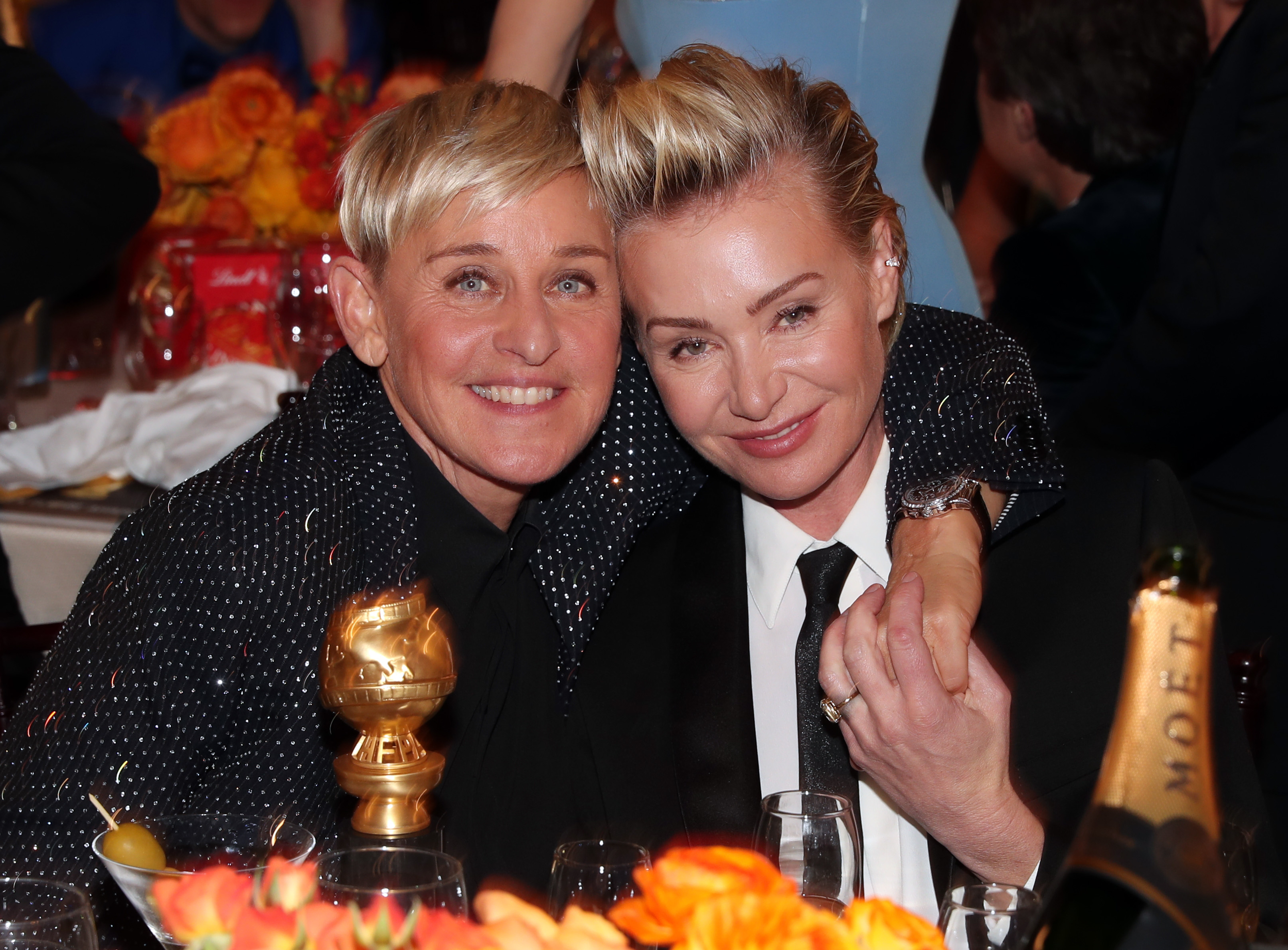 Ellen DeGeneres and Portia de Rossi smiling close together at an event, both dressed in stylish outfits