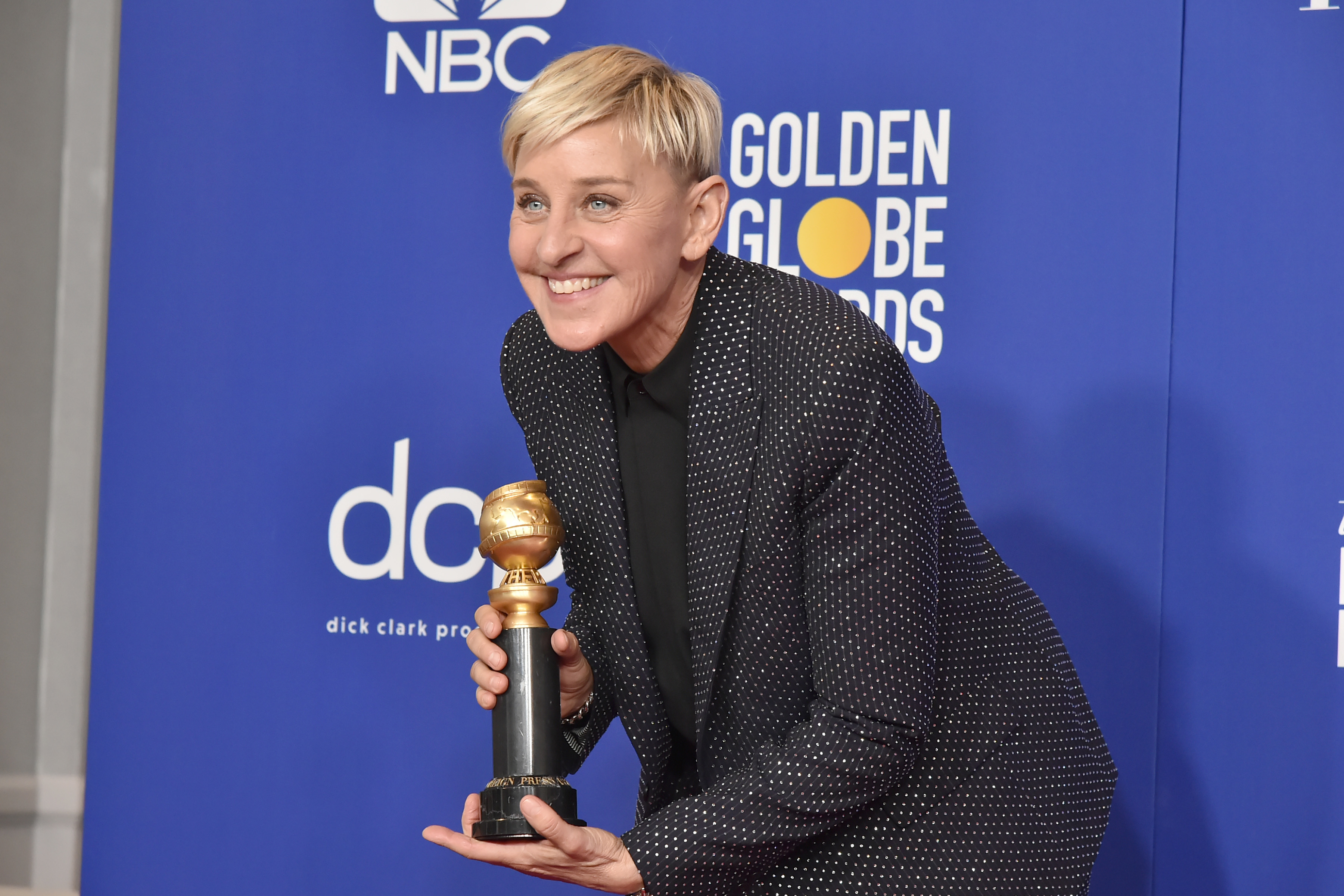 Ellen DeGeneres posing with a Golden Globe award, wearing a dotted suit