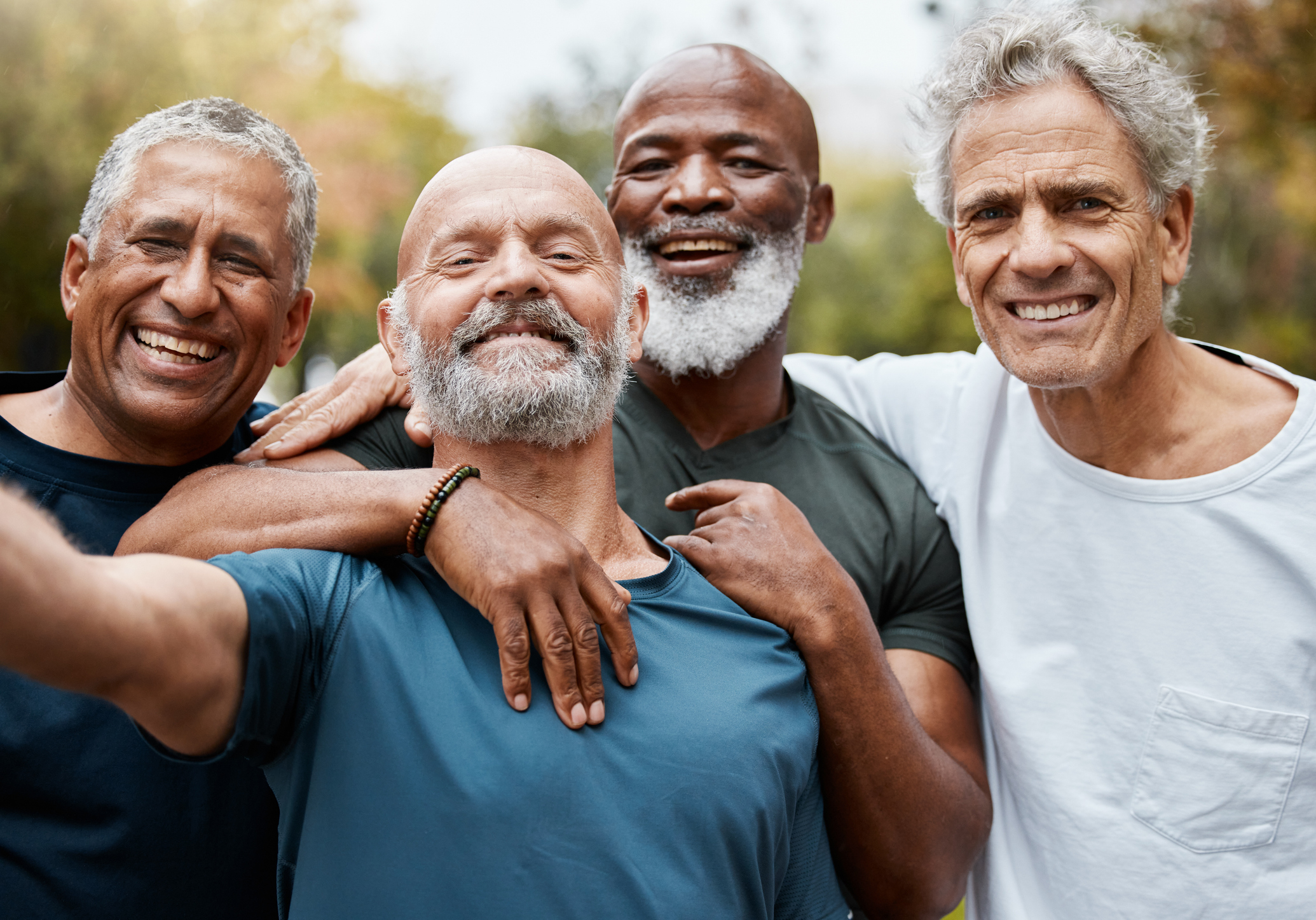 Four smiling elderly men embracing each other, portraying close friendship or relationships