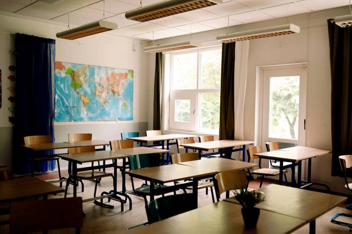 Empty classroom with desks, chairs, and a world map on the wall