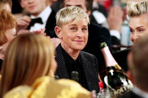 Ellen DeGeneres in a dotted suit at an event, surrounded by guests and champagne