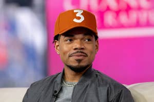 Chance the Rapper in a baseball cap, looking to the side, on a talk show set