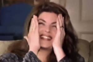 Kirstie Alley smiling with hands playfully covering their face