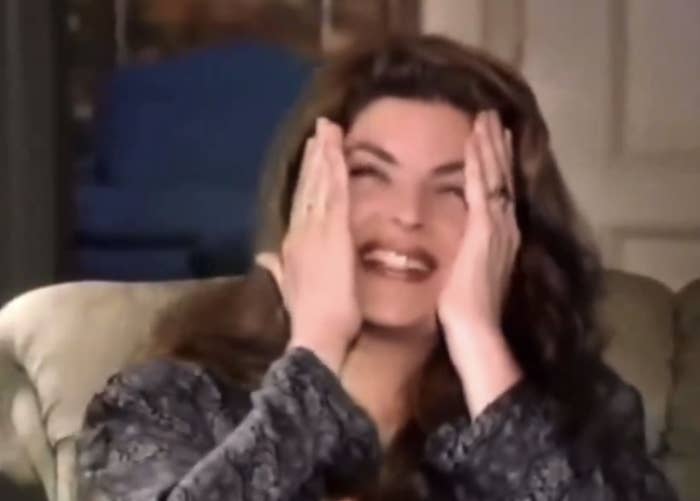 Kirstie Alley smiling with hands playfully covering their face