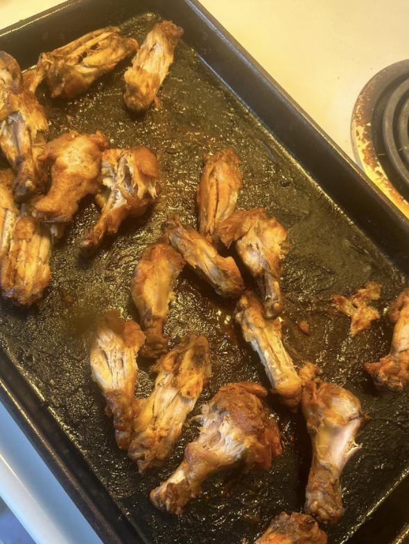 Baked chicken wings on a cooking tray with some charred areas