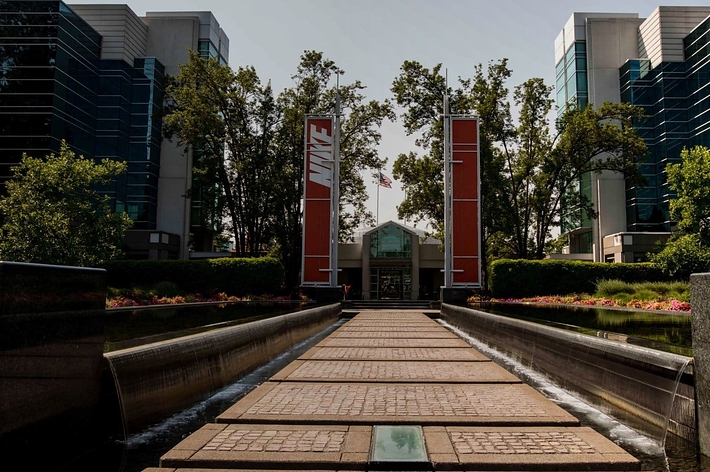 Entrance to Nike headquarters with large logo, reflecting water feature leading to the building