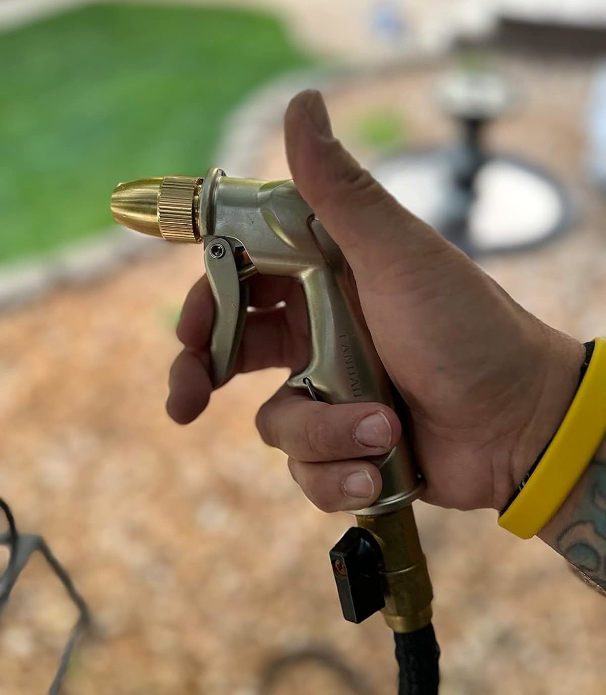 Hand holding a garden hose nozzle, ready to spray water