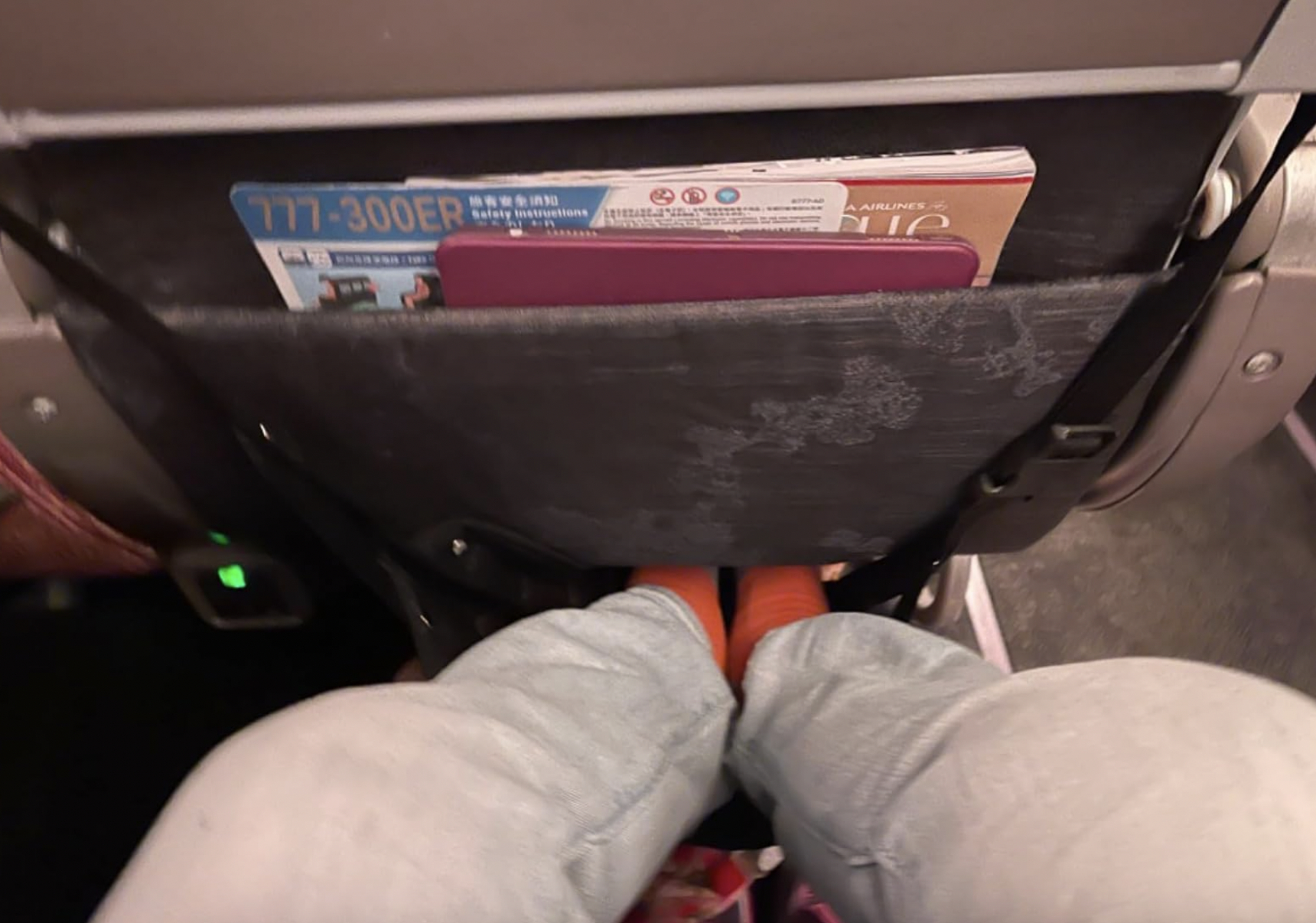 Passenger&#x27;s view of the back of an airplane seat with a safety card and seat pocket