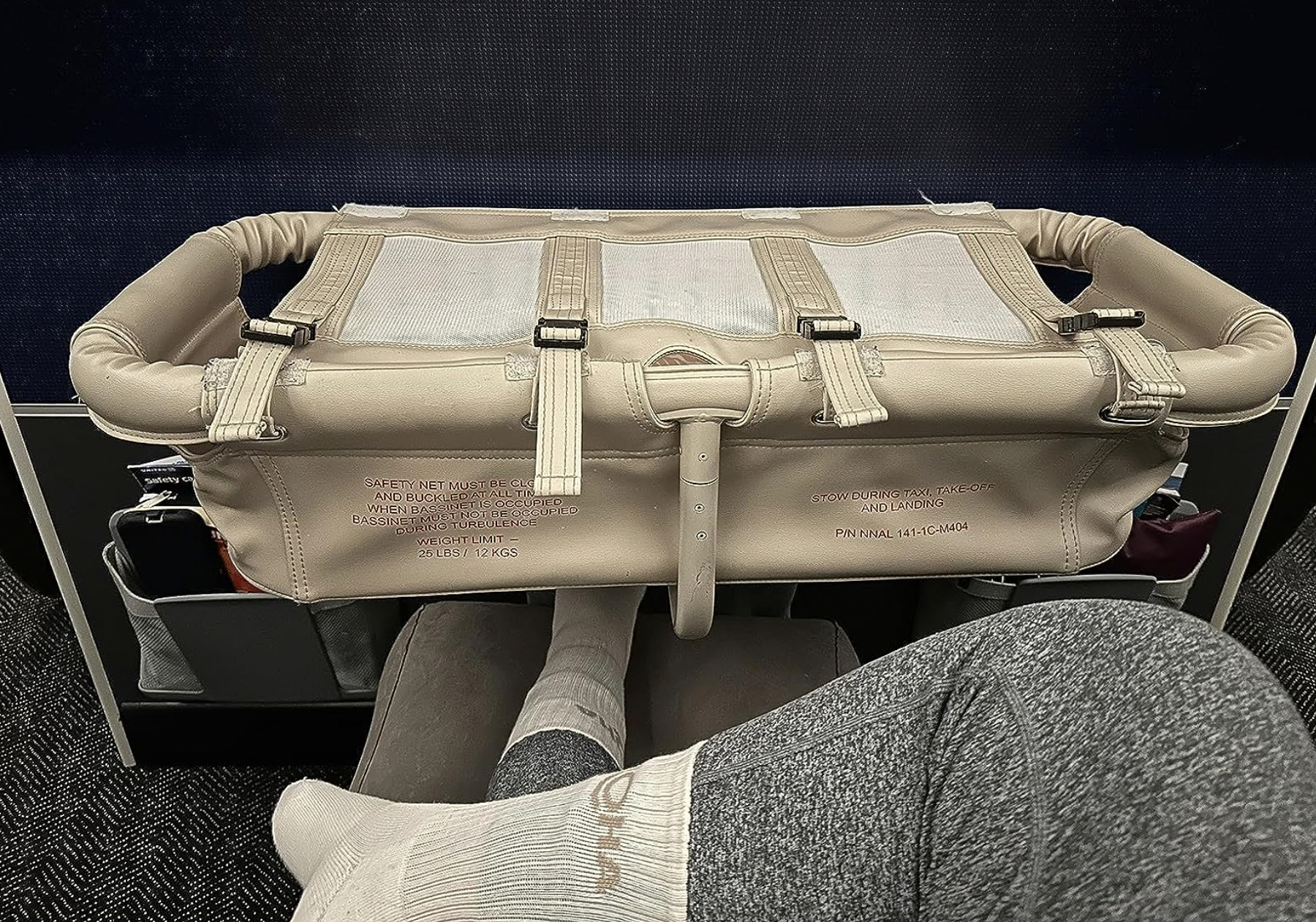 Passenger&#x27;s point of view of an airplane seat with a beige safety card holder and various safety instruction labels