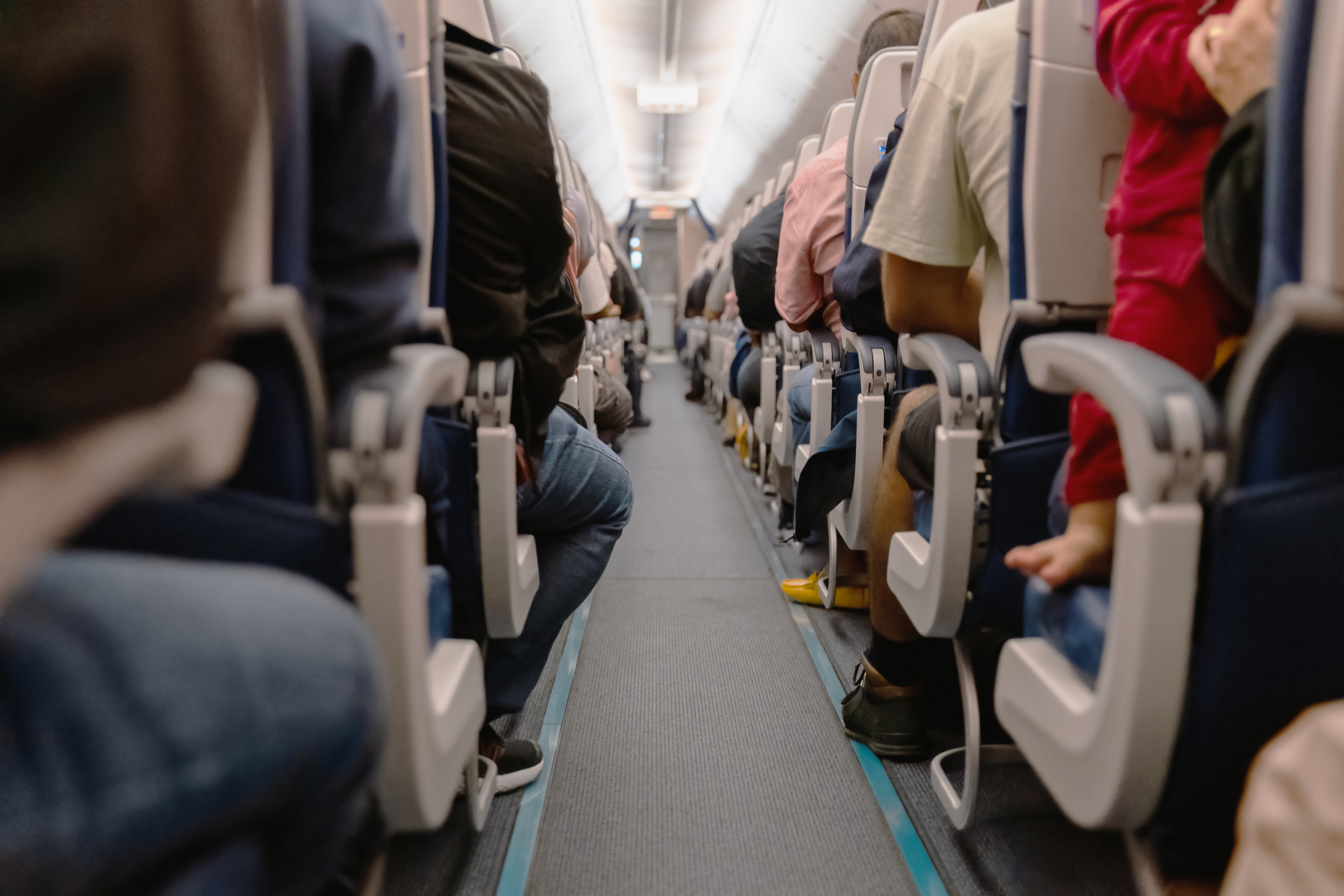 Passengers seated in an airplane aisle, focusing on the concept of business travel and work commute