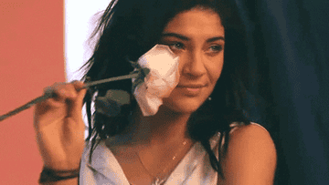 Woman smiling and holding a white rose to her face