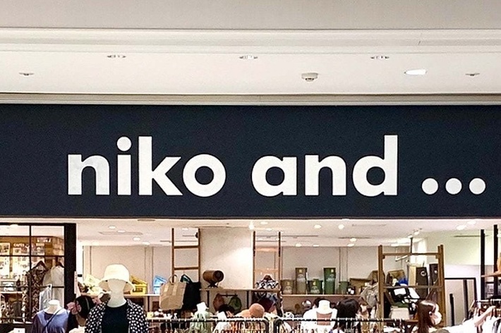 Storefront sign reading “niko and…” above a boutique with various items on display