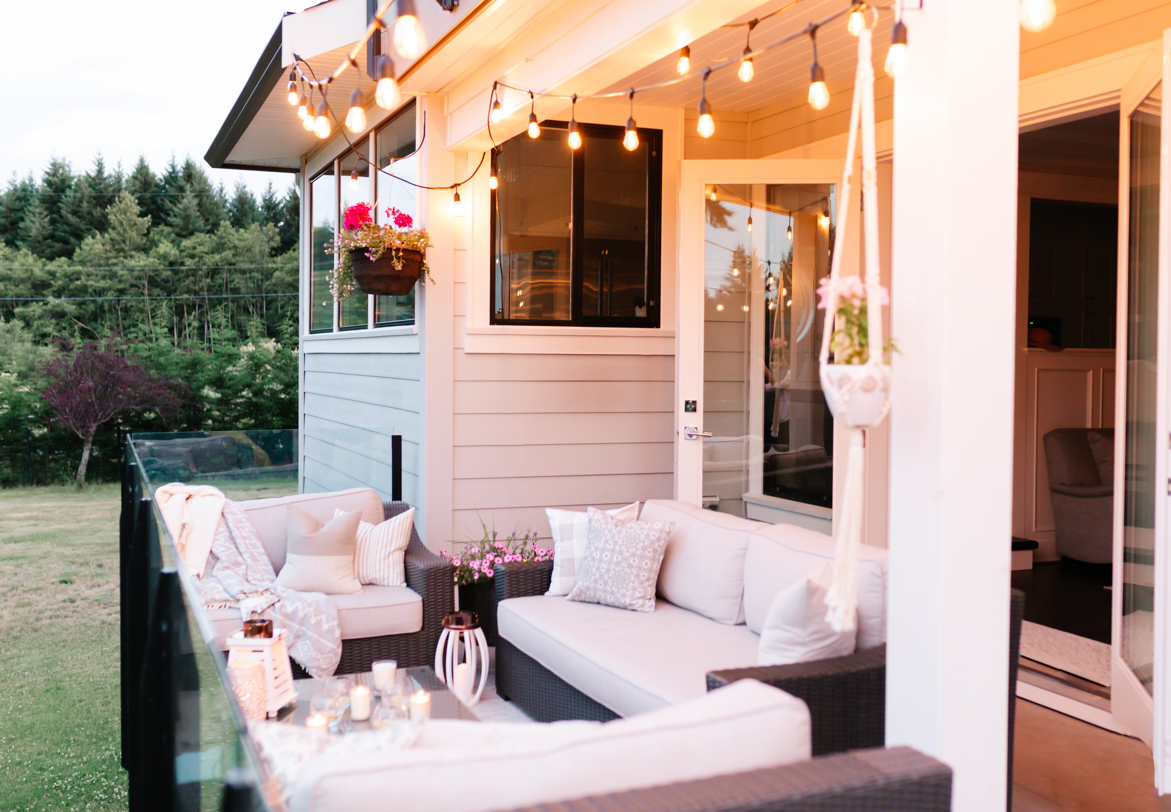 Cozy patio with string lights, cushioned seating and plants at dusk; no people visible. Used in lifestyle article