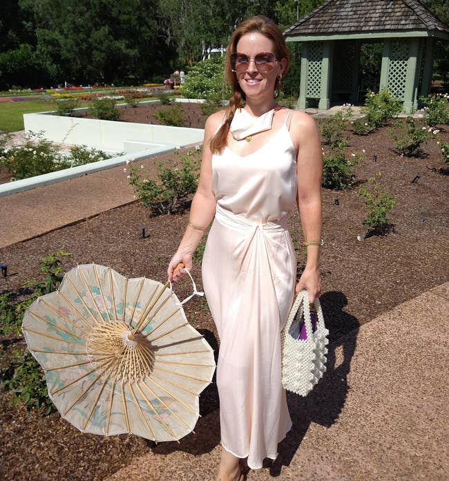 a reviewer wearing the disconnected achromatic silky cami with a silk skirt and a parasol portion outside