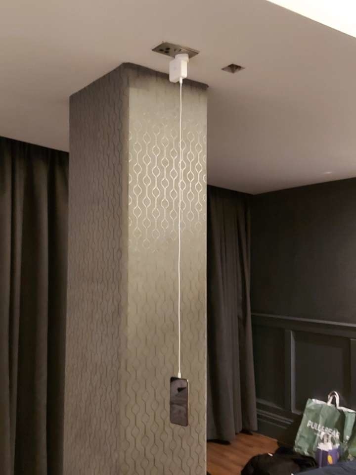 A shower head installed on a column in the middle of a room, with a curtain behind it