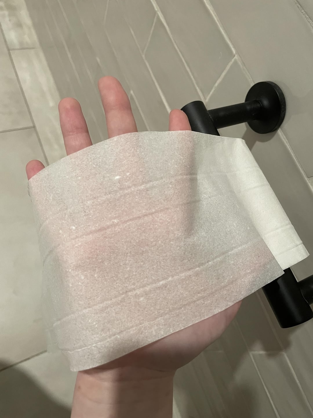 Hand holding a roll of translucent toilet paper