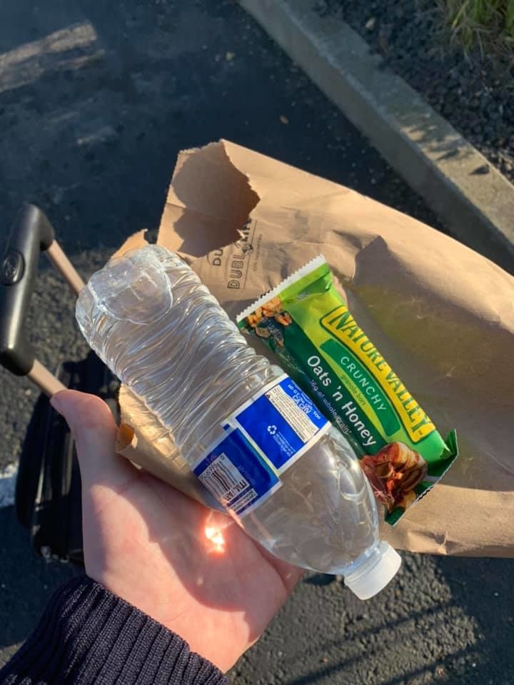 Person holding a plastic bottle and an empty snack wrapper, presumably trash picked up while walking
