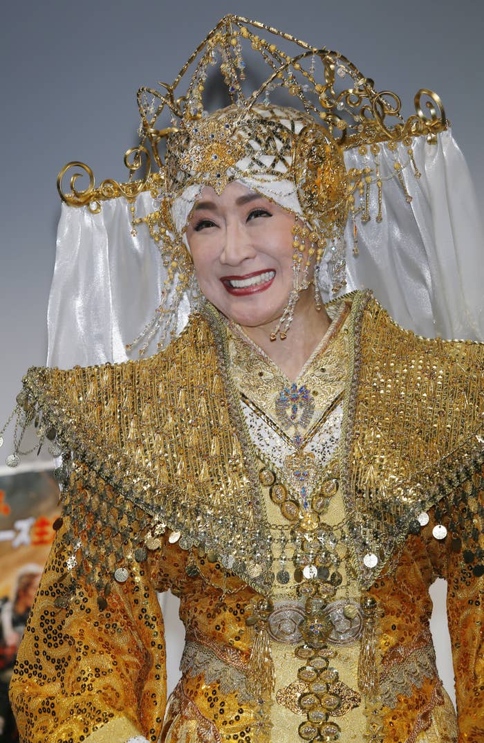 イベントでゴールド色の豪華な伝統衣装を着た笑顔の女性。