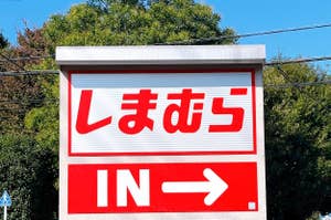 Sign with Japanese characters and "IN →" indicating an entrance to a location