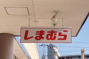 Sign with Japanese characters hanging outdoors under a ceiling