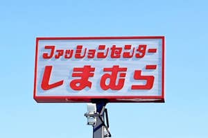 A red sign with Japanese characters against a clear sky on a post