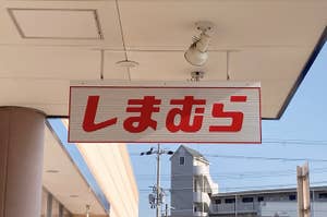 Sign with Japanese characters "Shimamura," a clothing retailer, hanging from a building's overhang