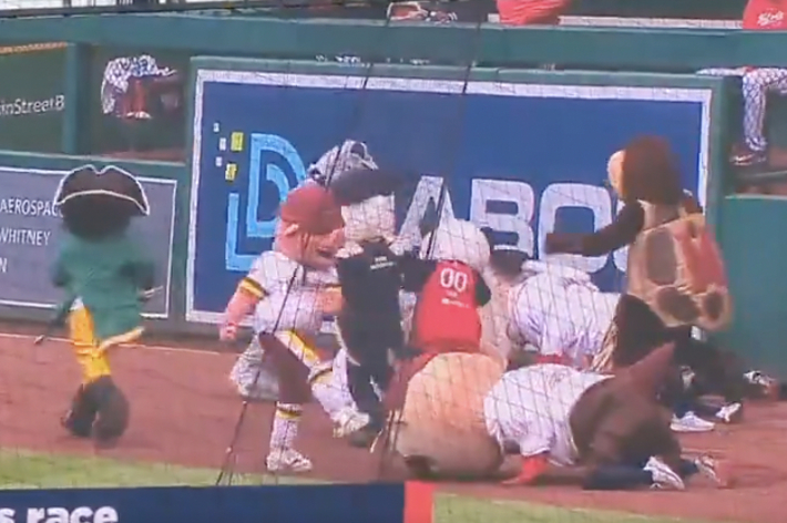 野球のマスコットが競争中、人々が地面に倒れている。