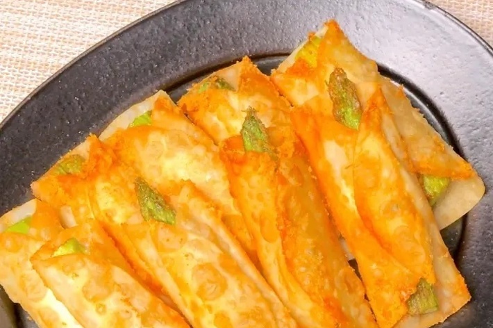 黒い皿に盛られた揚げたキムチ餃子。