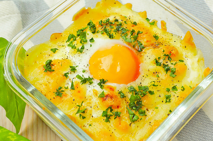 ガラス容器に入った目玉焼きとハム、パセリが振りかけられている。