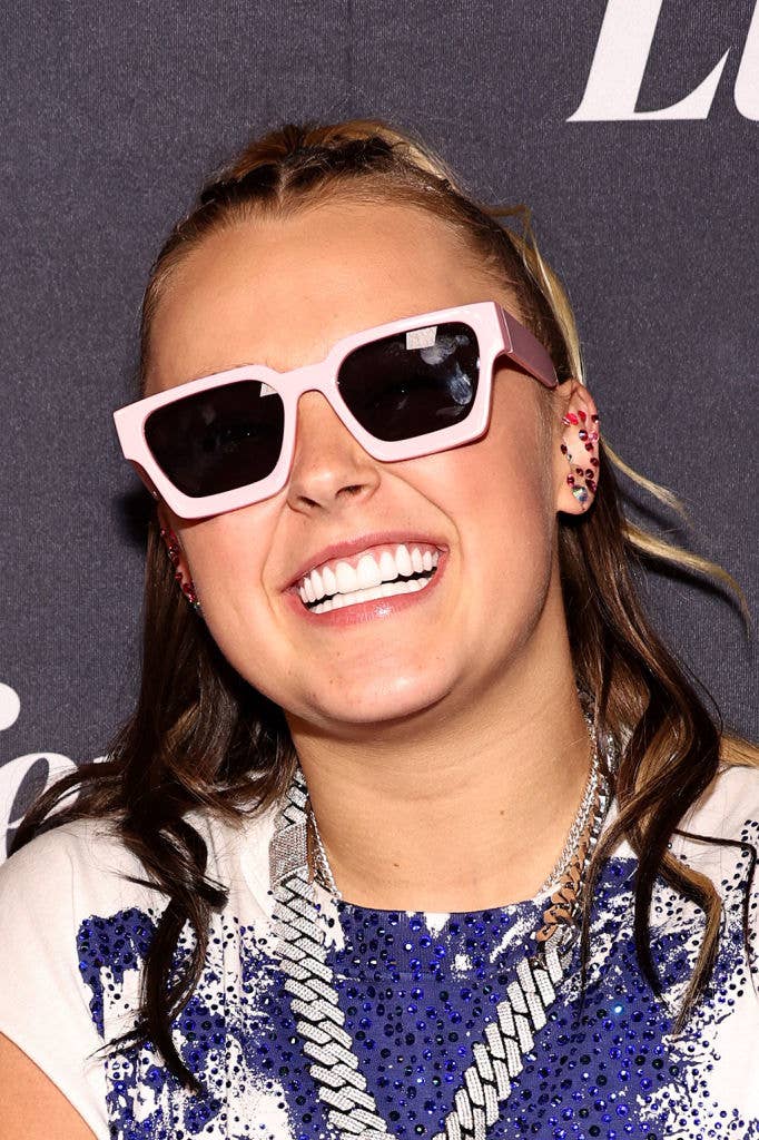 Person smiling, wearing oversized sunglasses and a sequined outfit